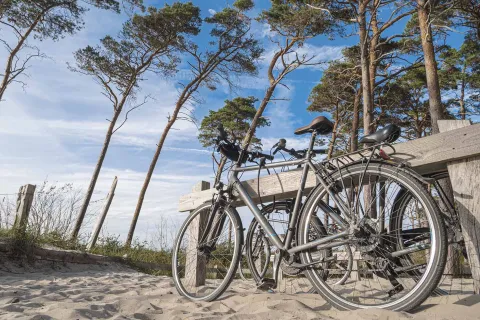 Zwei Fahrräder lehnen an einem Holzgestell am Strand von Fischland-Darß-Zingst an der Ostsee.