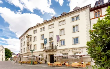 Das Hotel Elephant in Weimar in klassischer Architektur, mit Sonnenschirmen und Sitzgelegenheiten.