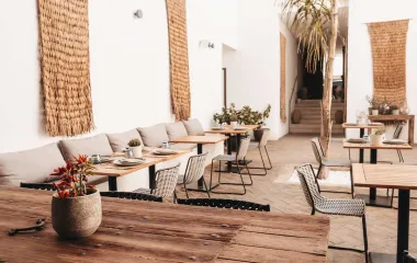 Blick in das moderne Barefoot Restaurant mit hellen Sesseln, Holzdekor und eingedeckten Tischen im Barefoot Hotel auf Mallorca.
