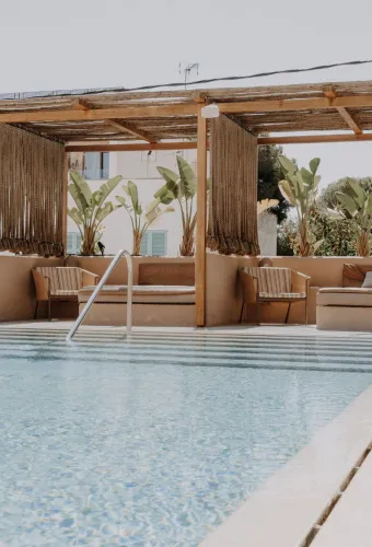 Moderner Pool mit gemütlichen Loungemöbeln und tropischen Pflanzen im Barefoot Hotel Mallorca, perfekt für das Herbstspecial.