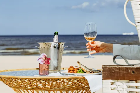 Ein gedeckter Strandtisch mit Fischgericht, Weißwein und Ostseeblick.