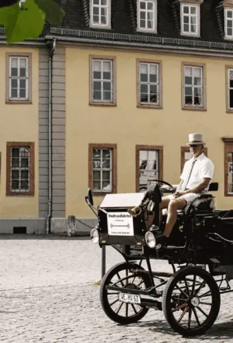Historische Kutsche mit Kutscher vor dem Goethehaus auf dem gepflasterten Frauenplan.