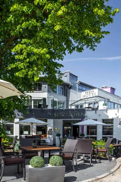 Sonnige Terrasse des Künstlerquartiers Seezeichen in Ahrenshoop mit Sitzgelegenheiten und grüner Umgebung.