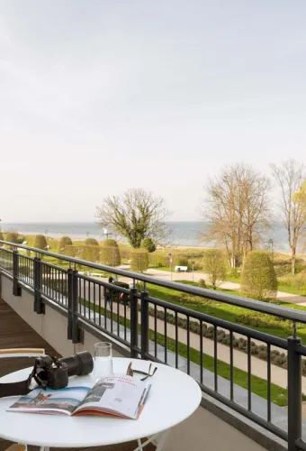 Balkon mit Sitzmöbeln, Tisch und direktem Blick auf die Ostsee und die Gartenanlage des Hotel Kaiserhofs Heringsdorf.