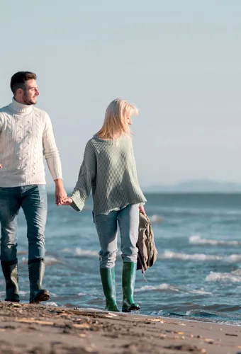 Pärchen beim Wandern am Strand mit Hund bei einem der zahlreichen Urlaubsangebote vom Vju Hotel.