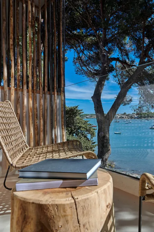 Balkon mit Stuhl, Tisch und Büchern vor einem Panoramaausblick auf das Meer im Barefoot Hotel Mallorca.