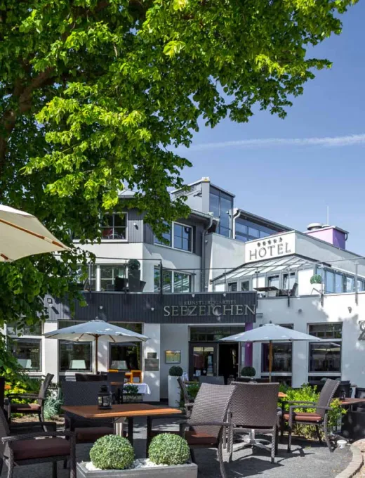 Sonnige Terrasse des Künstlerquartiers Seezeichen in Ahrenshoop mit Sitzgelegenheiten und grüner Umgebung.