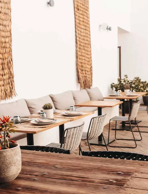 Blick in das moderne Barefoot Restaurant mit hellen Sesseln, Holzdekor und eingedeckten Tischen im Barefoot Hotel auf Mallorca.
