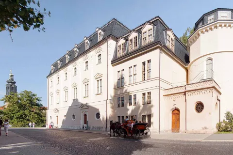 Außenansicht der Anna Amalia Bibliothek in Weimar mit historischem Turm und Pferdekutsche.