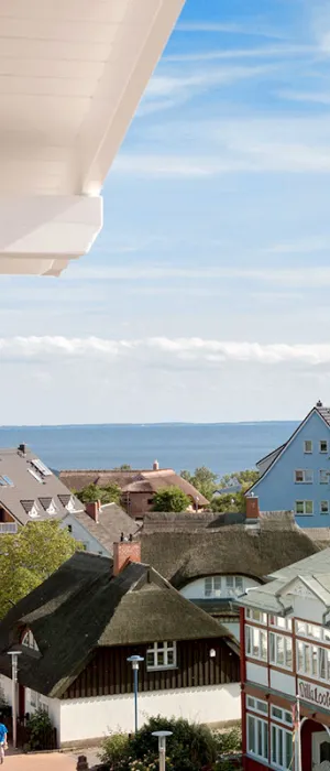 Blick vom Koopmanns Hotel über bunte Häuser und Reetdächer auf die Ostsee im Rahmen des Sommer Specials