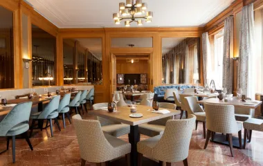 Blick in das elegante Restaurant Anna mit hellen Sesseln, Holzdekor und eingedeckten Tischen im Hotel Elephant in Weimar.