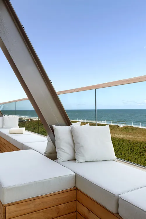 Sitzecke mit Polstern auf der Terrasse des Wyn. Strandhotels, die einen klaren Panoramablick auf die Nordsee bietet.
