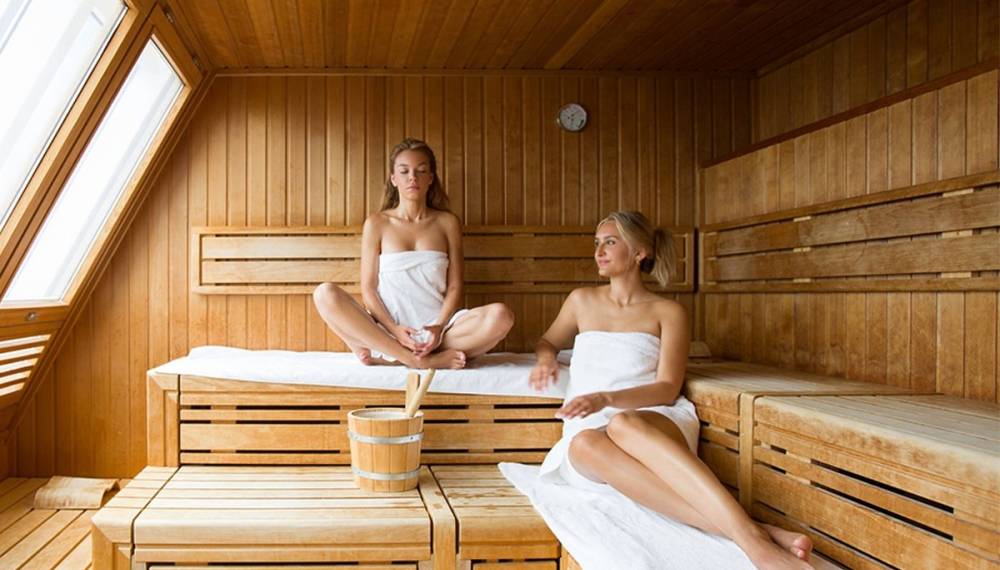 Zwei Freundinnen entspannen gemeinsam in einer Sauna und genießen eine wohltuende Auszeit.
