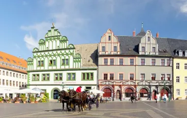 Blick auf die historische Innenstadt von Weimar mit Pferdekutsche und Menschen im Hintergrund.