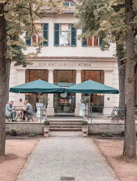 Gäste speisen auf der Terrasse vor dem Restaurant Zur Historischen Mühle in Potsdam.