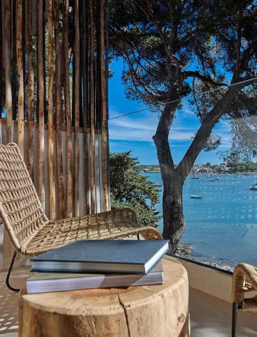 Terrasse mit Ausblick auf das Meer, Holzmöbel und mediterrane Landschaft im Barefoot Hotel Mallorca.