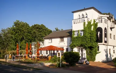 Außenansicht des Elisabeth von Eicken Hotel in Ahrenshoop mit Sonnenschirmen und blauem Himmel.
