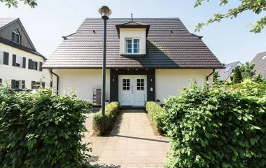 Haus der Residenz Seezeichen in Ahrenshoop mit dunklem Dach, Hecken und gepflastertem Weg.