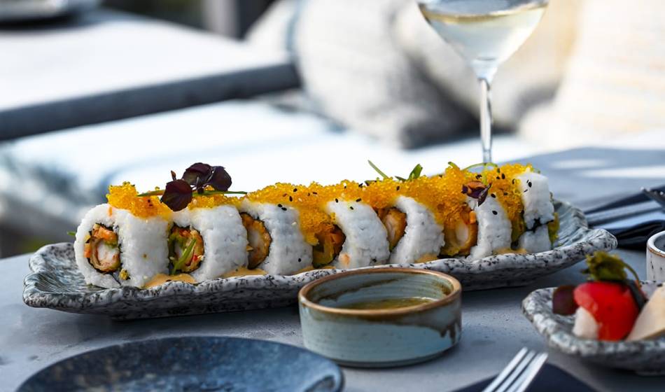 Sushi-Rollen mit Kaviar und Gemüsefüllung, dekorativ auf einer Platte angerichtet, begleitet von einem Glas Weißwein im #herrhoshi.