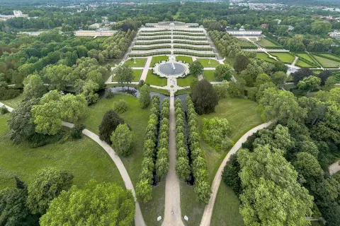 Park Sanssouci von oben mit den Wegen, der Fontäne und Schloss Sanssouci in der Mitte. Im Hintergrund ist Potsdam zu sehen.