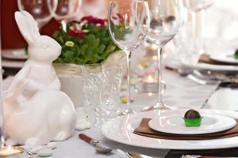 Ein elegant gedeckter Ostertisch mit einer Praline auf einem Teller und Hasen-Dekoration, umgeben von Gläsern.