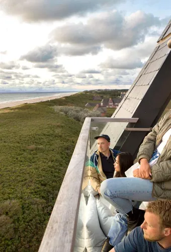 Gruppe entspannt auf dem Balkon des Wyn Strandhotel Sylt mit Blick auf Strand und Dünen