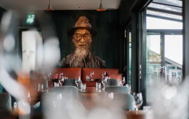 Stilvoll eingedeckter Innenraum des Restaurants #herrhoshi mit Porträtmalerei im Hotel Künstlerquartier Seezeichen in Ahrenshoop.