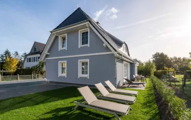 Ferienhaus Sonneninsel mit blauer Fassade, Garten, Sonnenliegen und sonnigem Himmel in Ahrenshoop.