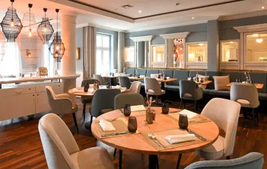 Blick in das maritime Restaurant Küstensilber mit hellen Stühlen und Bänlen, Holzdekor und eingedeckten Tischen im Vju Hotel auf Rügen.