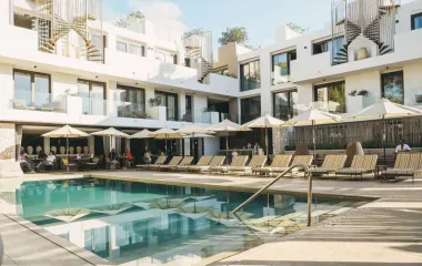 Blicken Sie auf das Barefoot Hotel in Mallorca, umgeben von sonnigen Liegen, Sonnenschirmen und einem erfrischenden Pool.