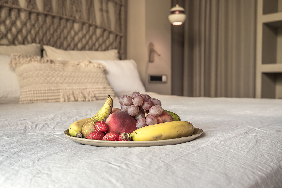 Bienvenido al Barefoot Hotel Mallorca con una bandeja de fruta fresca sobre su cama en la Habitación Doble Confort Puerto.