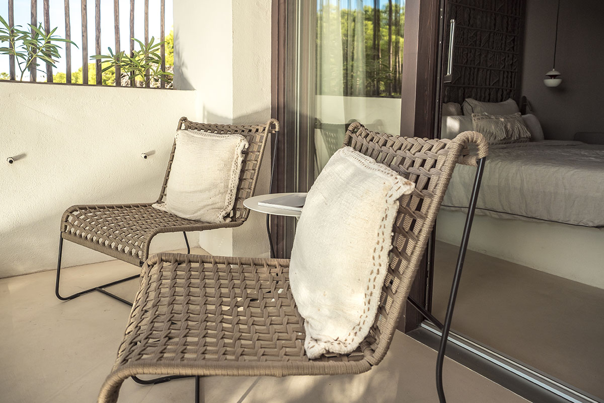 Balcón privado en la habitación doble Mar del Barefoot Hotel Mallorca con dos elegantes sillas, cojines y una pequeña mesa.