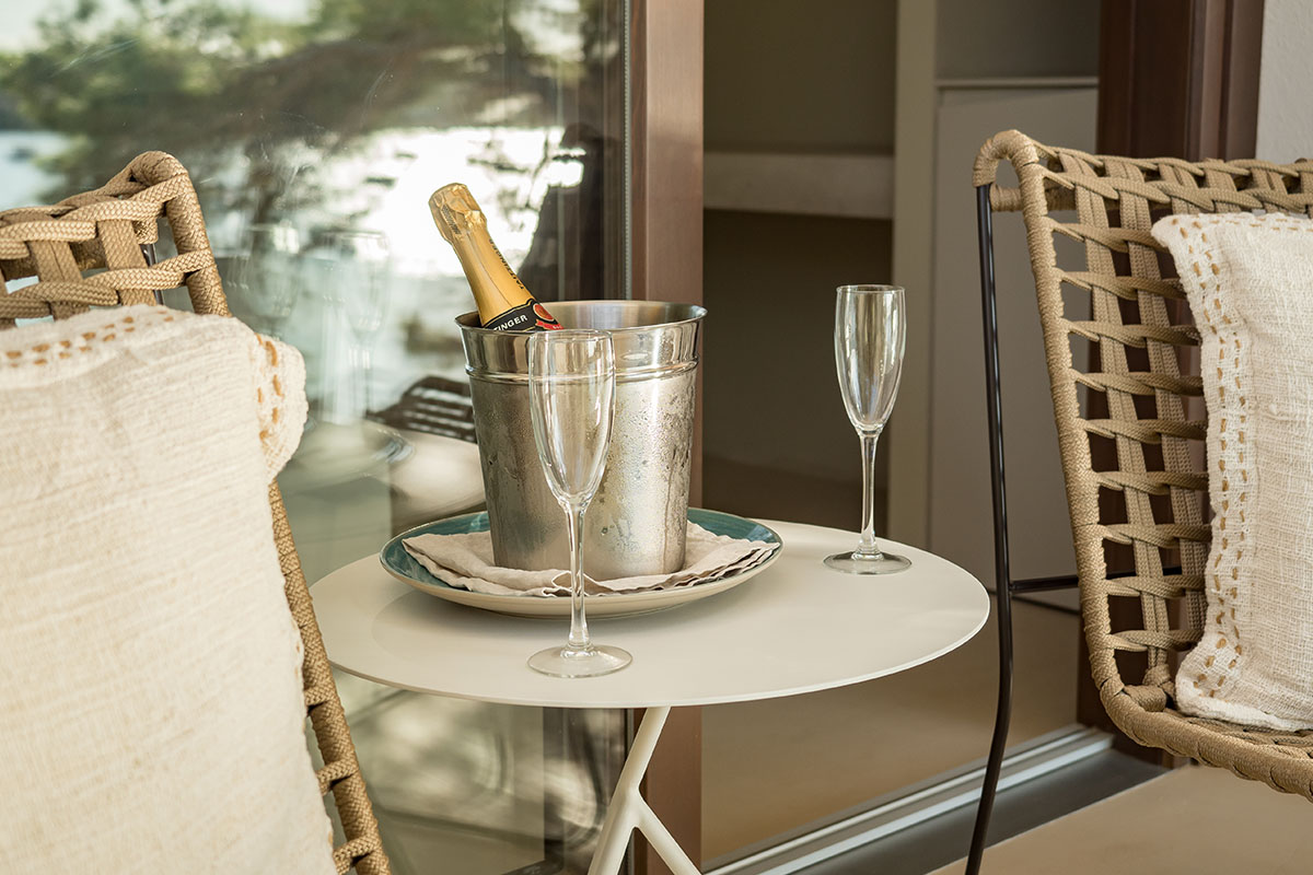 Botella de Champagne en una nevera con dos copas en una mesa en la terraza de la habitación doble Mar en el Hotel Descalzos Mallorca.