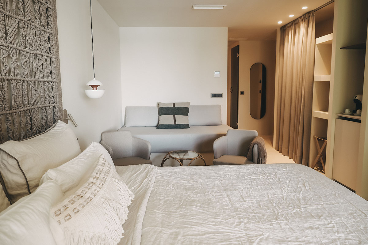 Luminosa zona de estar con sofá y sillones en la elegante habitación doble Mar del Hotel Pies Descalzos de Mallorca.