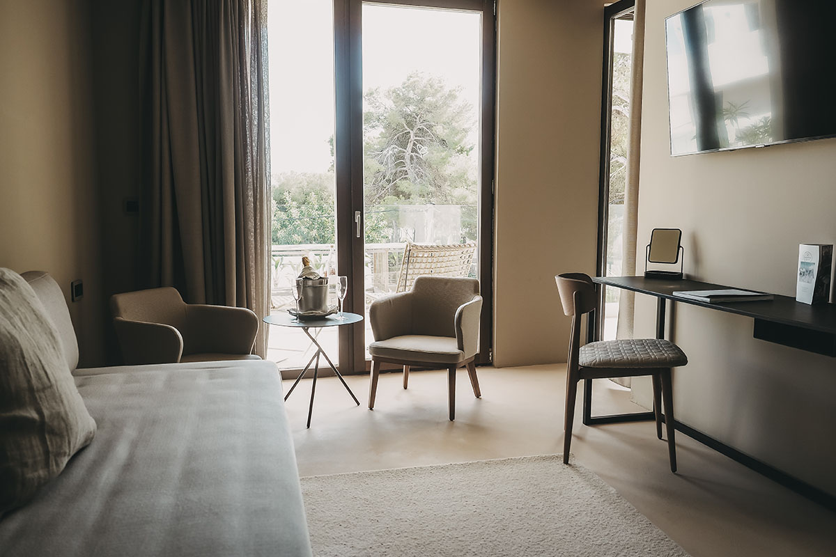 Zona de estar de la Habitación Doble Deluxe Oasis del Hotel Pies Descalzos de Mallorca con sofá, sillones, escritorio y acceso al balcón.