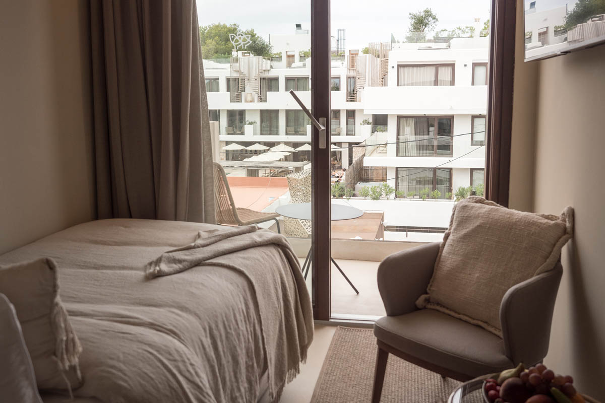 Habitación compartida en el Barefoot Hotel Mallorca con cama individual, sillón y balcón con vistas al recinto del hotel.