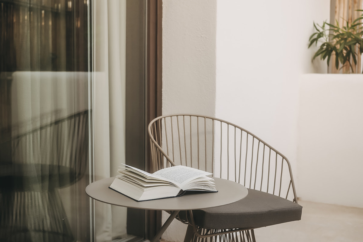 Gemütlicher Balkon im Zimmer Pino des Barefoot Hotel Mallorca mit Sitzgelegenheit, Tisch und aufgeschlagenem Buch.