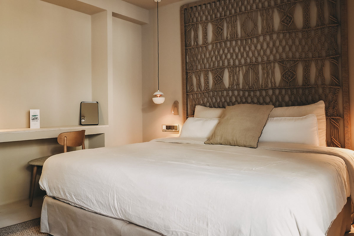Gemütliches Bett im Zimmer Pino des Barefoot Hotel Mallorca mit dekorativem Kopfteil und Kissen.