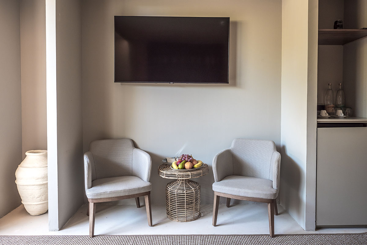 Gemütliche Sitzecke im Zimmer Pino des Barefoot Hotel Mallorca mit zwei Sesseln, Rattantisch und Obstschale.