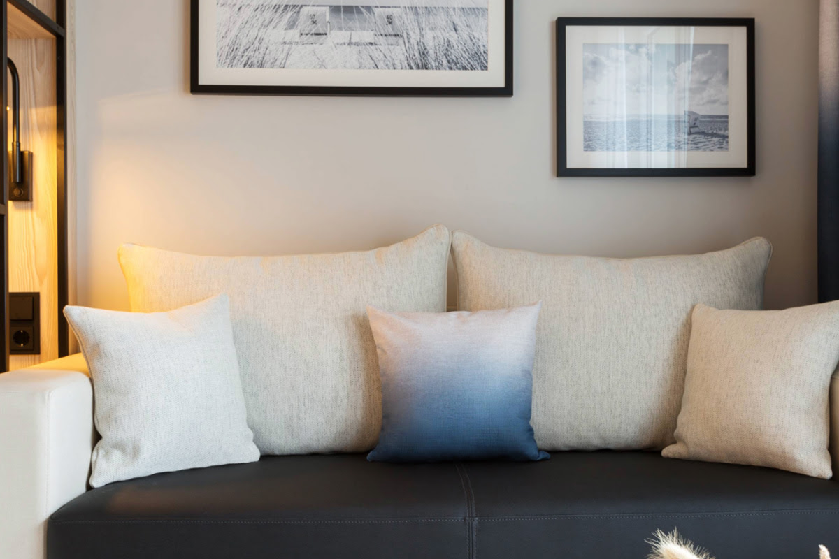 Helle Sofaecke mit dekorativen Kissen und Wandbildern im Hintergrund im Doppelzimmer im Hotel Kaiserhof Heringsdorf.