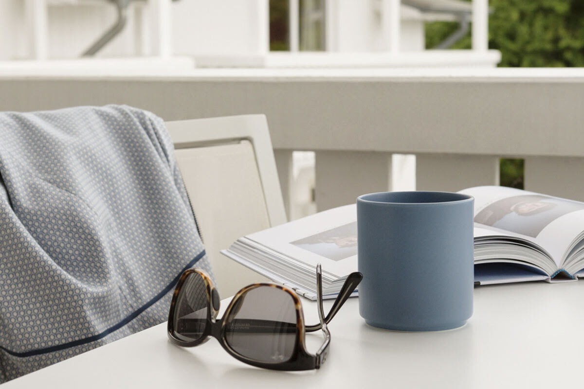 Close-up of a cup of coffee, sunglasses and book on the balcony at the Koopmanns Hotel &amp; Lädchen on the island of Rügen.