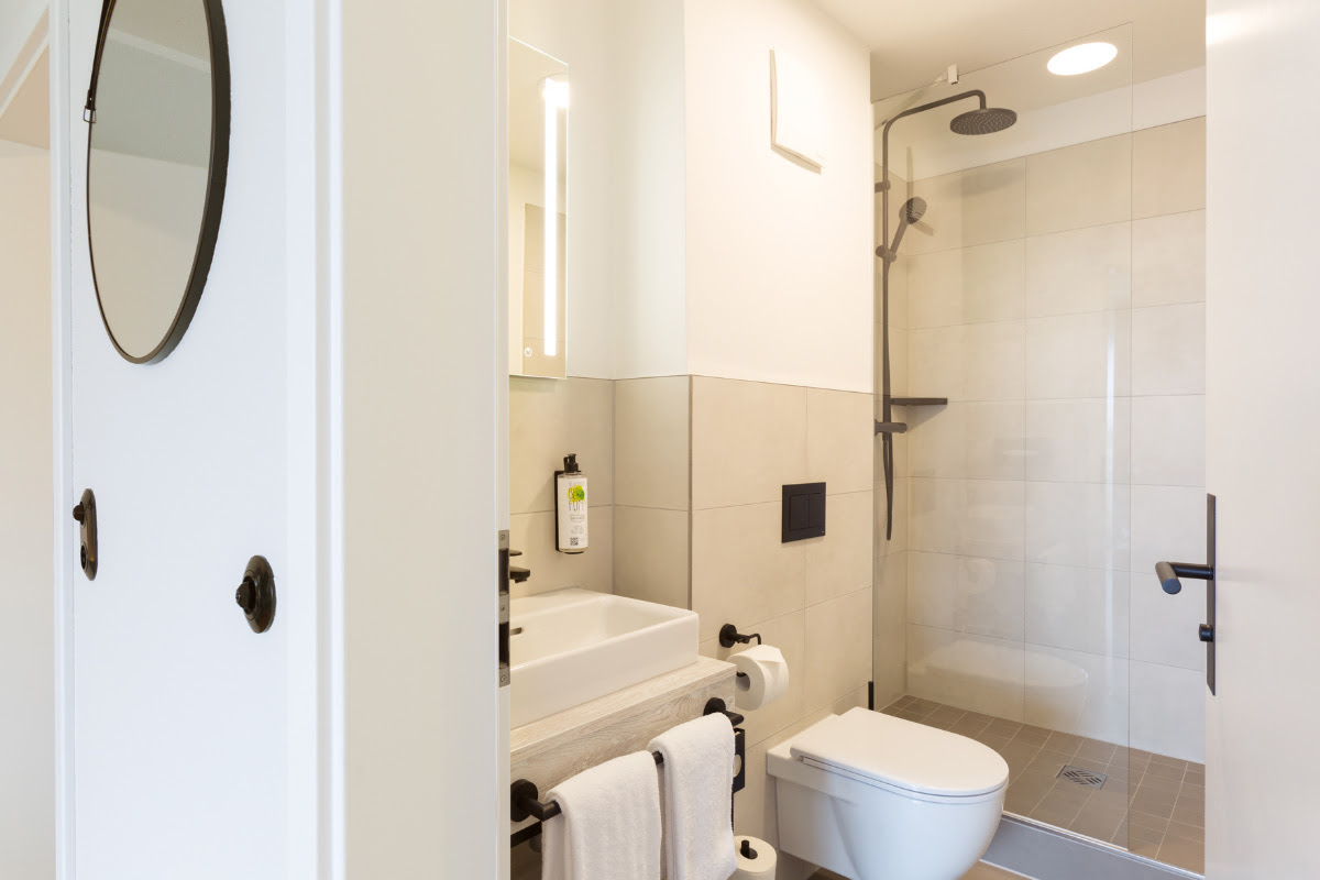 Modern bathroom with rain shower, washbasin, mirror and WC in the comfort double room at the Koopmanns Hotel.