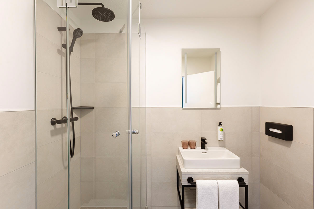 Bathroom with rain shower, washbasin and modern design for relaxation at the Koopmanns Hotel.