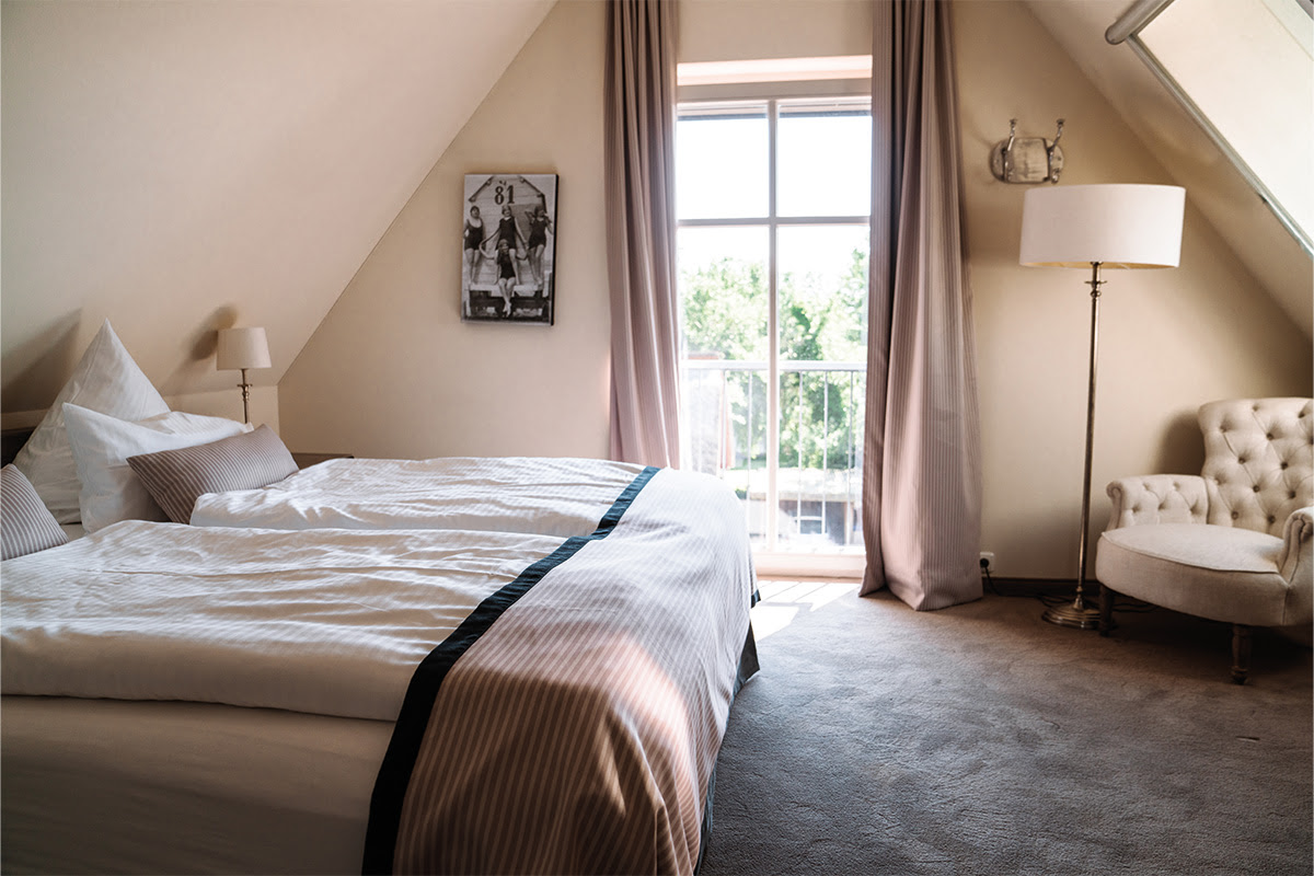 Modernes Schlafzimmer in der Ferienwohnung Dünenpark im Hotel Künstlerquartier Seezeichen mit großem Bett und Seeblick.