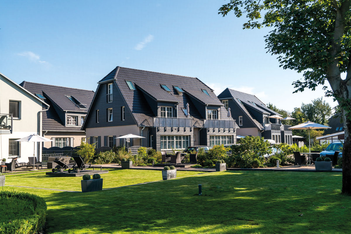 Außenansicht der Ferienwohnung Seeigel mit gepflegtem Garten und sonniger Terrasse des Hotels Künstlerquartier Seezeichen.