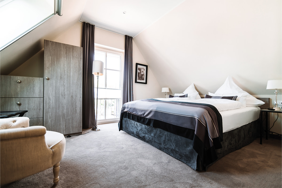 Modern eingerichtetes Schlafzimmer mit gemütlichem Bett in der Ferienwohnung Strandduene im Hotel Künstlerquartier Seezeichen.