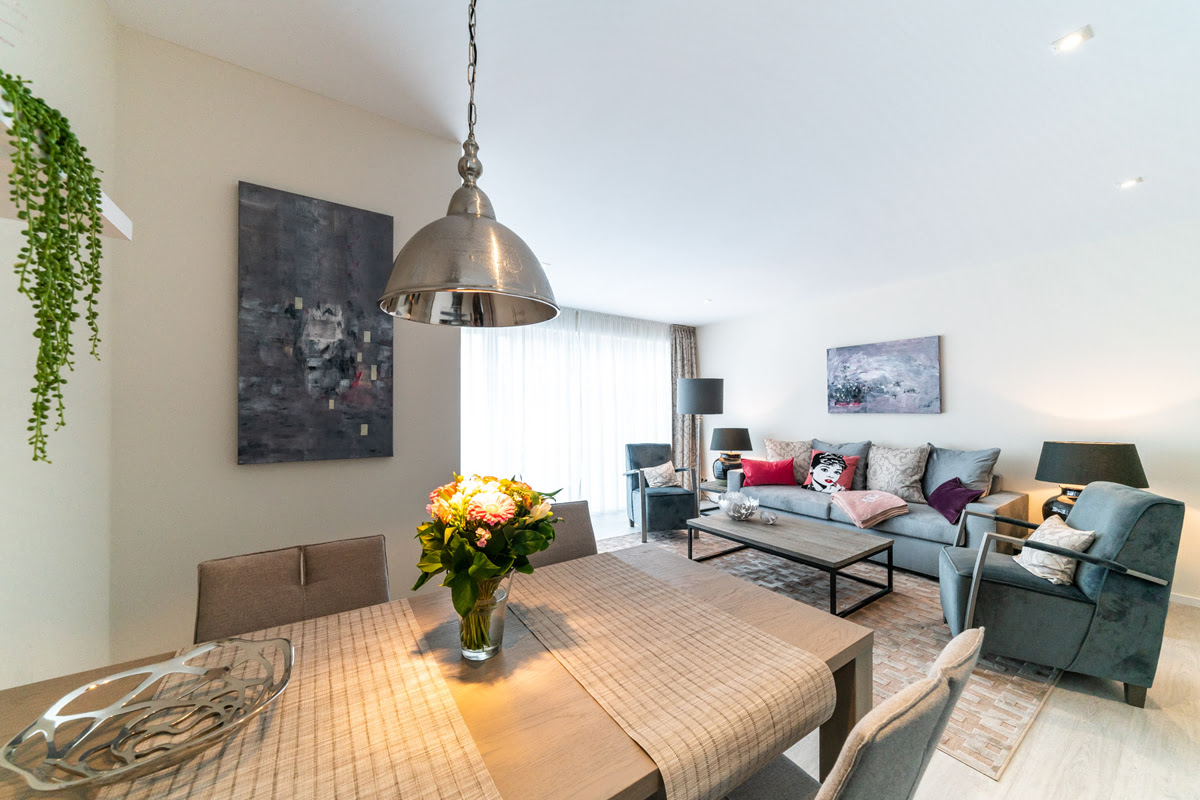 Essbereich mit Esstisch, gepolsterten Stühle und Blick in den Wohnraum der Ferienwohnung Strandliebe im Künstlerquartier Seezeichen.