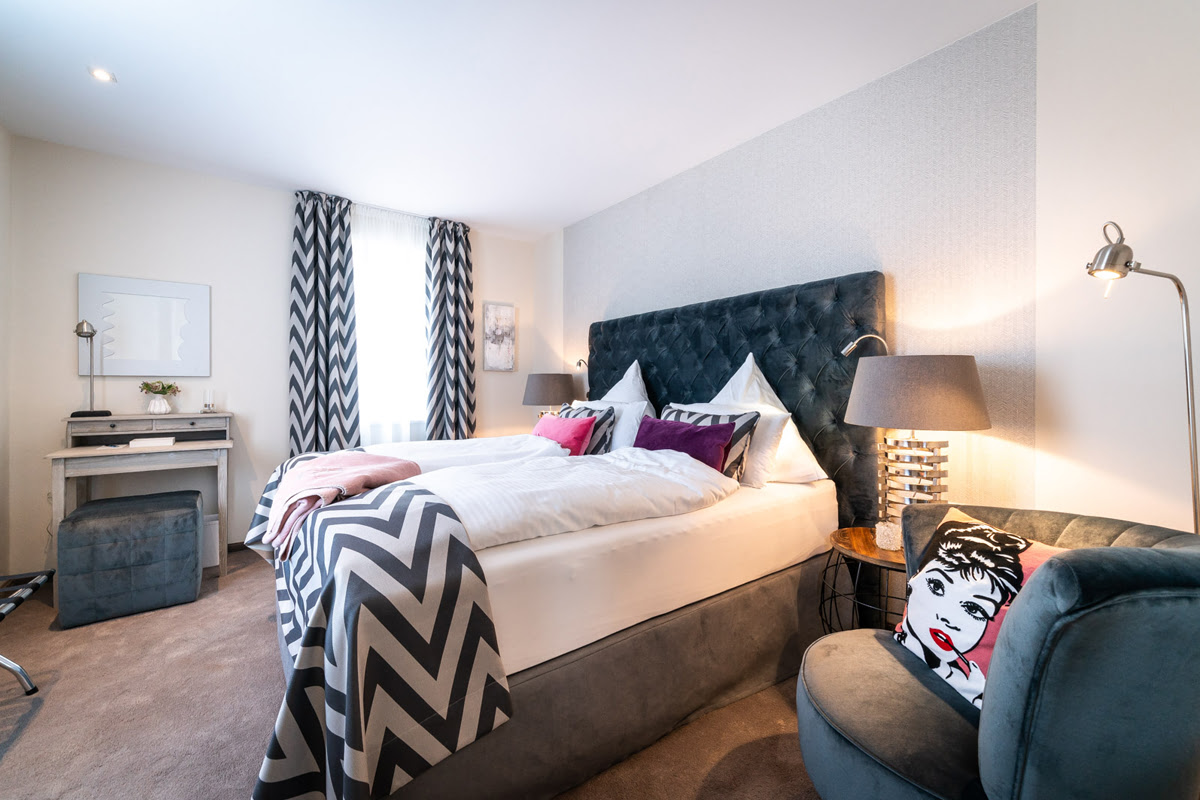 Stilvolles Schlafzimmer mit Boxspringbett und dekorativen Akzenten in der Ferienwohnung Strandliebe im Künstlerquartier Seezeichen.