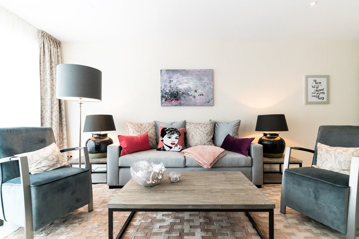 Wohnbereich mit Sofa, zwei Sesseln und dekorativen Elementen in der Ferienwohnung Strandliebe im Hotel Künstlerquartier Seezeichen.