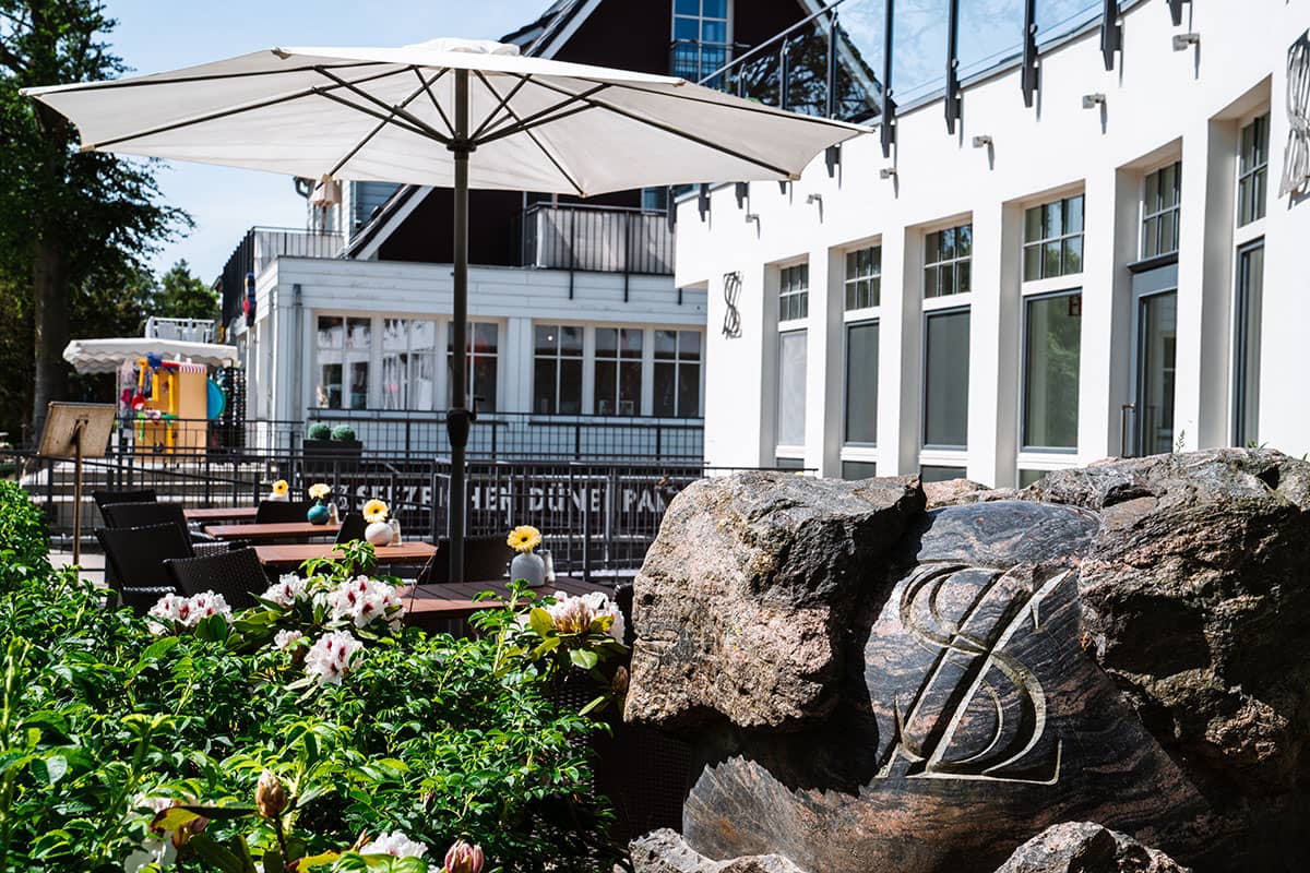 Terrasse des Hotel Künstlerquartier Seezeichen mit Sonnenschirm und Blumen bei einem Aufenthalt im Zimmer Seezeichen.